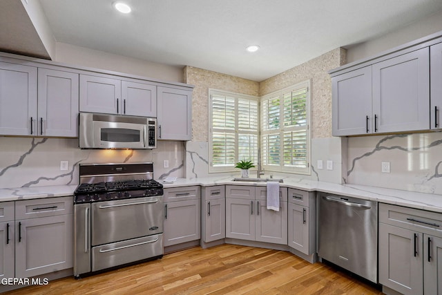 909 Singing Hills Dr, El Paso, TX 79912 - kitchen with appliances with stainless steel finishes, gray cabinets, light wood-style floors, light stone counters, and tasteful backsplash