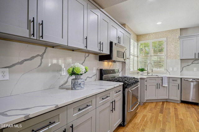 909 Singing Hills Dr, El Paso, TX 79912 - kitchen featuring stainless steel appliances, light wood-style floors, tasteful backsplash, light stone counters, and a sink