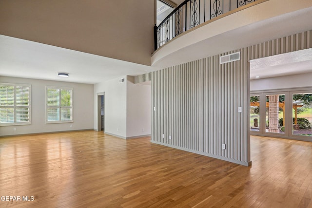 909 Singing Hills Dr, El Paso, TX 79912 - unfurnished living room with wood finished floors, a towering ceiling, and baseboards