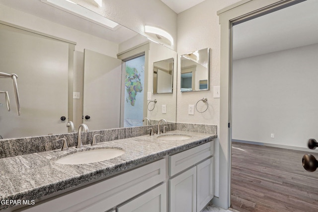 909 Singing Hills Dr, El Paso, TX 79912 - bathroom featuring wood finished floors, double vanity, and baseboards