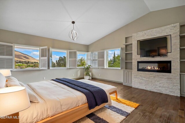 909 Singing Hills Dr, El Paso, TX 79912 - bedroom featuring vaulted ceiling, dark wood-type flooring, a stone fireplace, and baseboards