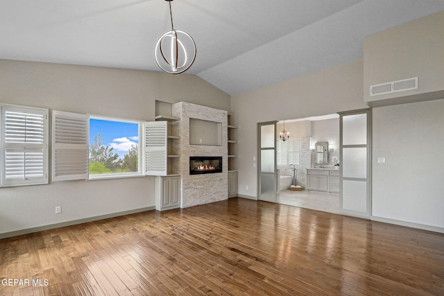 909 Singing Hills Dr, El Paso, TX 79912 - unfurnished living room with a chandelier, high vaulted ceiling, a glass covered fireplace, wood finished floors, and baseboards