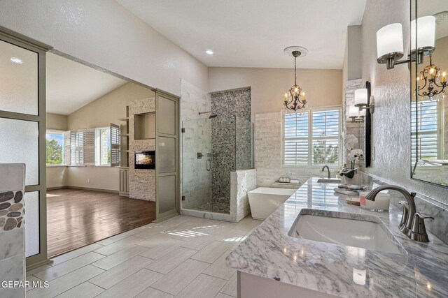 909 Singing Hills Dr, El Paso, TX 79912 - bathroom with a chandelier, vaulted ceiling, a stall shower, double vanity, and wood finished floors
