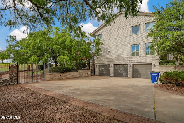 909 Singing Hills Dr, El Paso, TX 79912 - view of property exterior with a garage, concrete driveway, fence, a gate, and brick siding