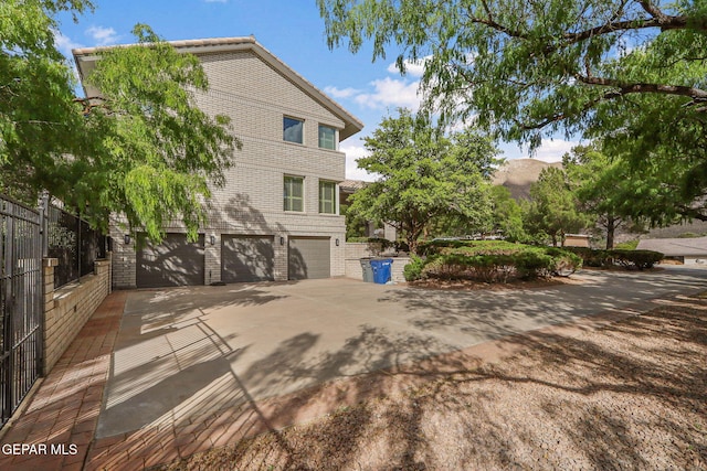 909 Singing Hills Dr, El Paso, TX 79912 - view of side of home with an attached garage, brick siding, driveway, and fence