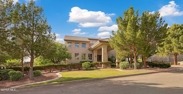 909 Singing Hills Dr, El Paso, TX 79912 - view of front of home with brick siding, a tile roof, and a front lawn