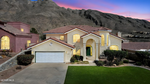 mediterranean / spanish house with a tiled roof, a garage, concrete driveway, stucco siding, and a mountain view