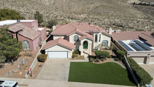 view of front facade featuring a tiled roof, a chimney, a garage, concrete driveway, and stucco siding