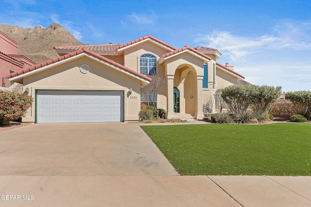 mediterranean / spanish house with a tile roof, concrete driveway, stucco siding, an attached garage, and a front yard