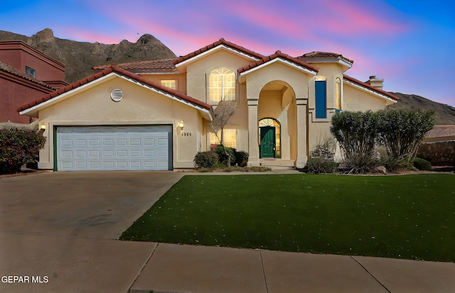 mediterranean / spanish-style home featuring a tile roof, concrete driveway, stucco siding, and a lawn