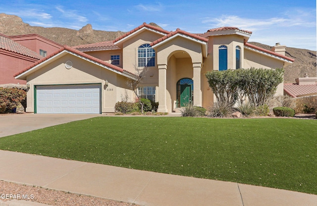 mediterranean / spanish house with driveway, a front lawn, a tiled roof, and stucco siding
