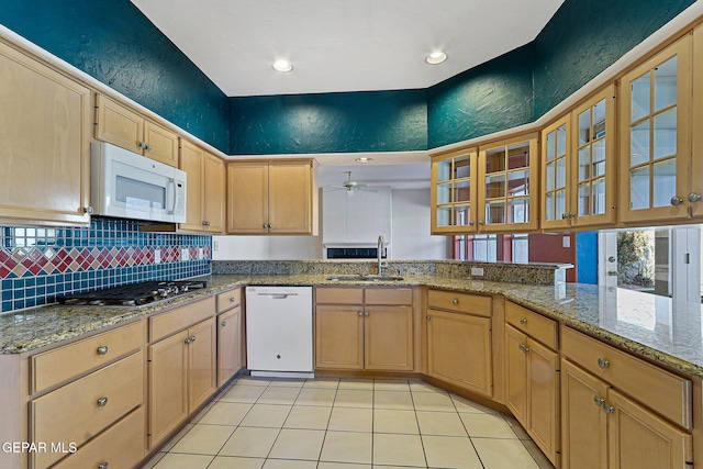 kitchen with white appliances, a textured wall, a sink, ceiling fan, and glass insert cabinets