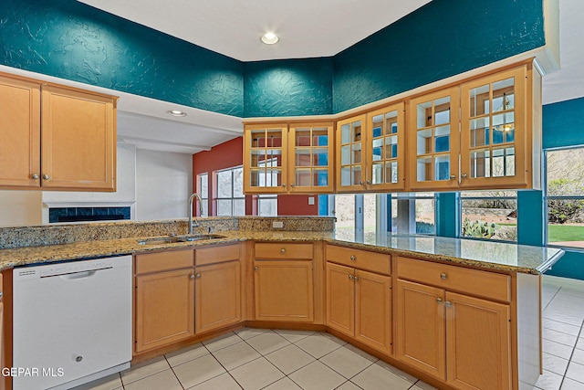 kitchen with a fireplace, a sink, white dishwasher, and glass insert cabinets