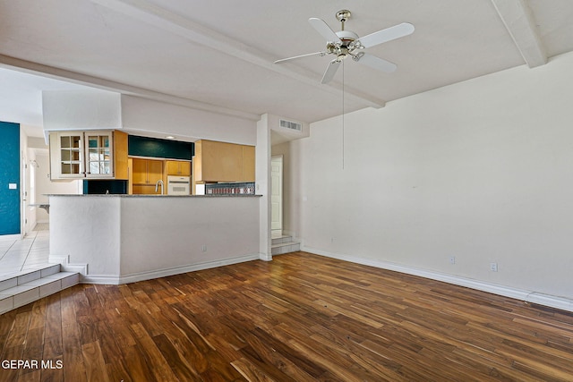 unfurnished living room with a ceiling fan, lofted ceiling with beams, wood finished floors, baseboards, and visible vents