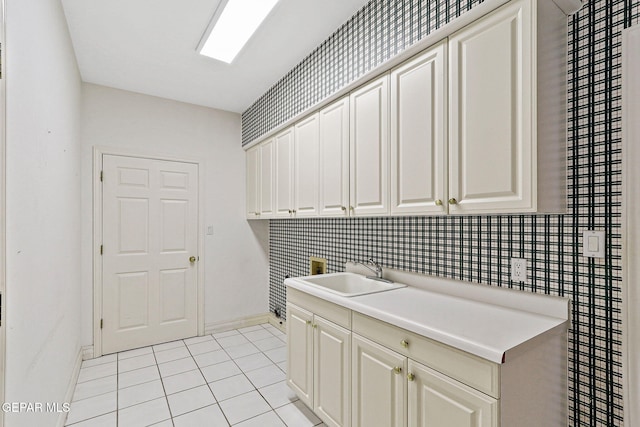 laundry area with baseboards, cabinet space, a sink, and light tile patterned floors