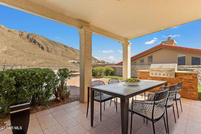 view of patio with area for grilling, outdoor dining area, fence, and an outdoor kitchen