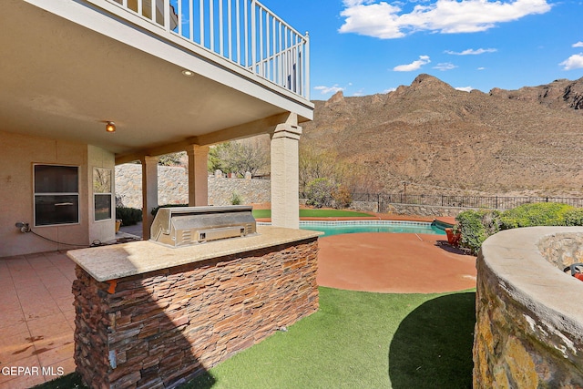 view of patio / terrace featuring exterior kitchen, a fenced backyard, a fenced in pool, and a mountain view