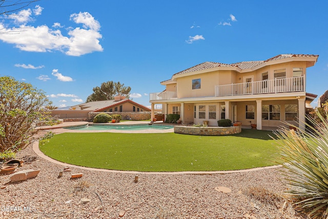 rear view of house featuring a fenced in pool, stucco siding, a balcony, a fenced backyard, and a tiled roof