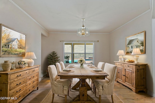 dining space featuring ornamental molding, a notable chandelier, and light wood finished floors