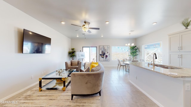 tiled living room with sink, ceiling fan with notable chandelier, and a wealth of natural light