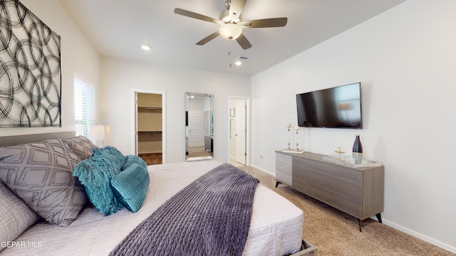 bedroom featuring light carpet, a spacious closet, and ceiling fan