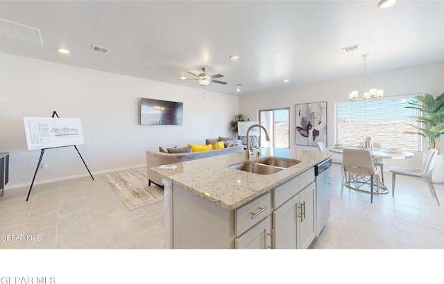 kitchen with pendant lighting, sink, dishwasher, light stone countertops, and a center island with sink