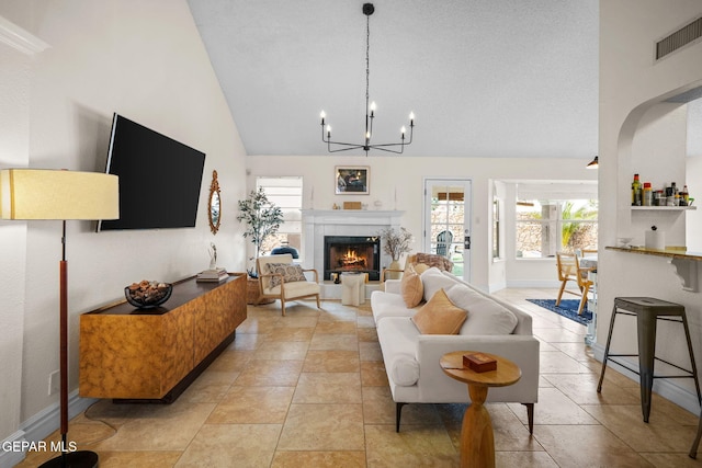 living room with a tiled fireplace, high vaulted ceiling, and a chandelier