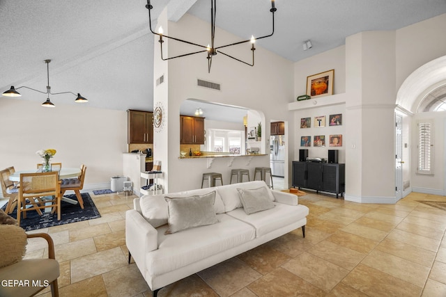 living room with an inviting chandelier, high vaulted ceiling, and a textured ceiling