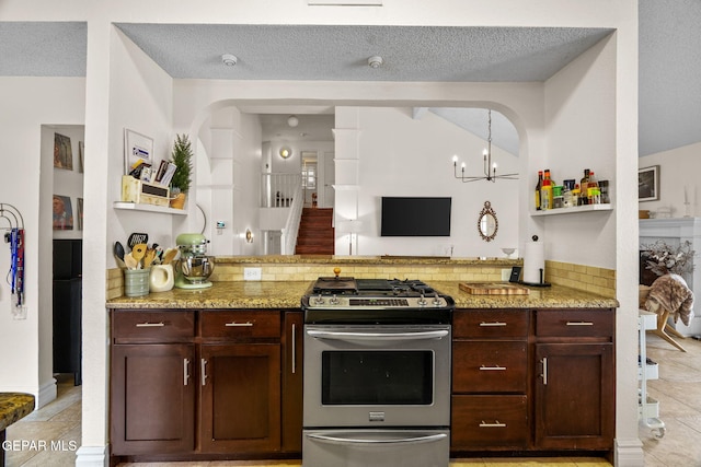 kitchen featuring hanging light fixtures, stainless steel range with gas stovetop, light stone counters, a notable chandelier, and a textured ceiling