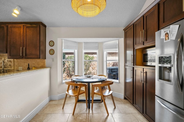 kitchen featuring appliances with stainless steel finishes, light stone countertops, a textured ceiling, and backsplash