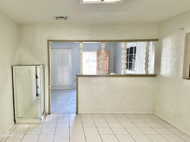 empty room with light tile patterned flooring and a textured ceiling