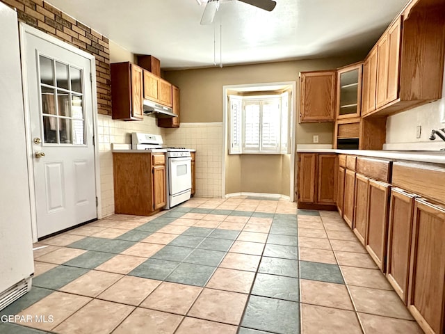 kitchen featuring tile walls, ceiling fan, light tile patterned floors, and white gas stove