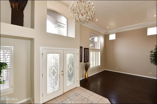 tiled entryway featuring an inviting chandelier, french doors, crown molding, and a high ceiling