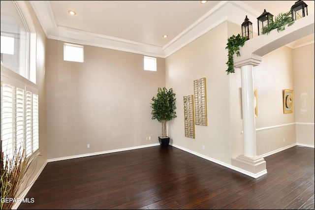 unfurnished room with plenty of natural light, dark wood-type flooring, and decorative columns