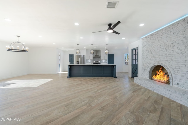 unfurnished living room featuring ceiling fan, a fireplace, and light hardwood / wood-style floors