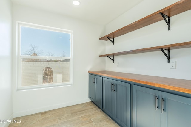 bar with butcher block counters and light hardwood / wood-style flooring