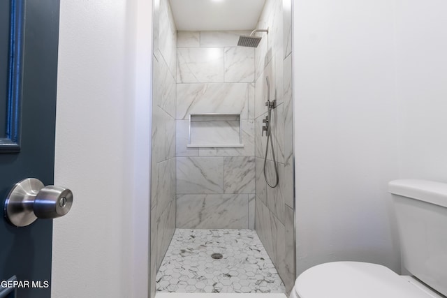 bathroom with a tile shower and toilet