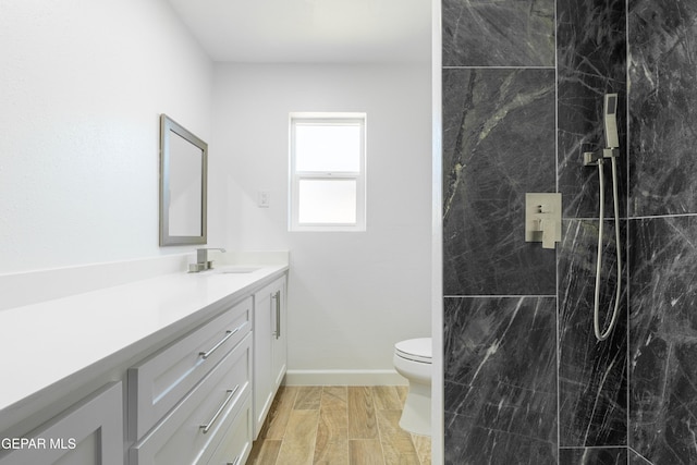 bathroom featuring vanity, toilet, and a tile shower