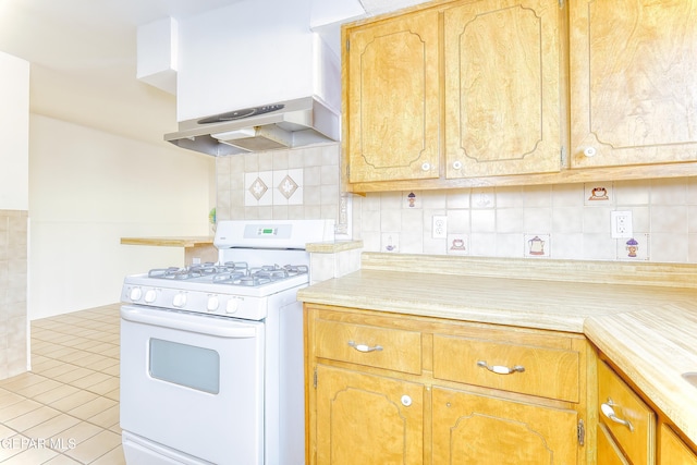 kitchen with light tile patterned flooring, white gas range oven, and decorative backsplash