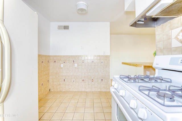 kitchen with white appliances, tile walls, white cabinets, light tile patterned flooring, and exhaust hood