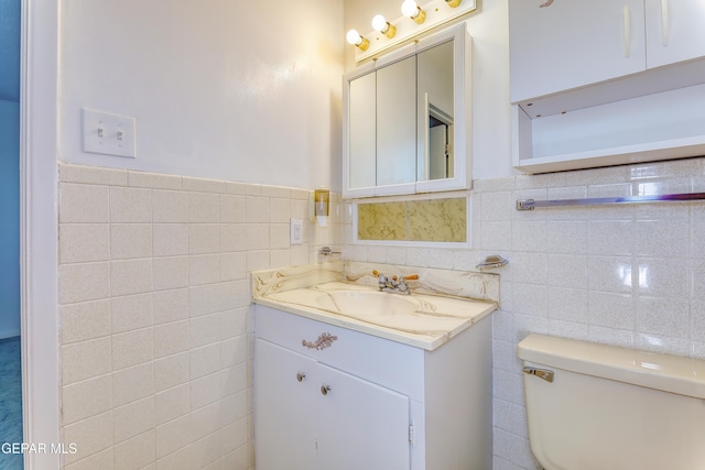 bathroom featuring vanity, toilet, and tile walls