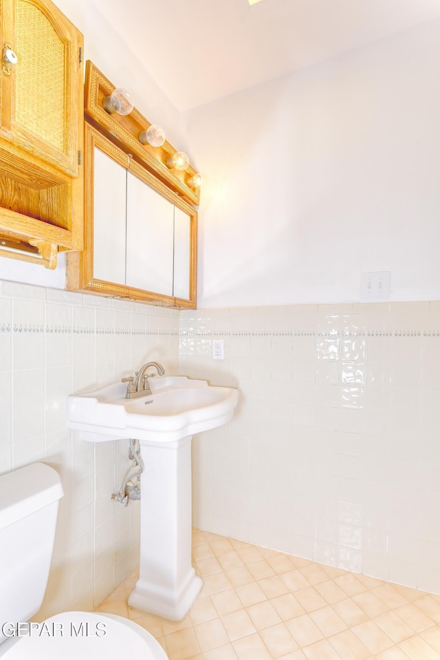 bathroom featuring tile patterned flooring, tile walls, and toilet