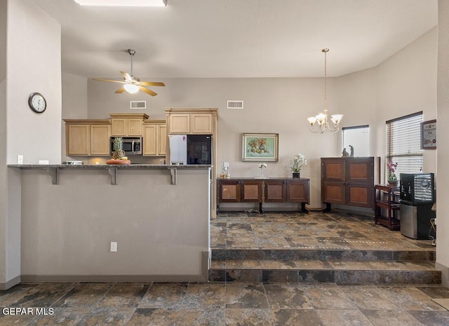 kitchen featuring appliances with stainless steel finishes, a towering ceiling, ceiling fan with notable chandelier, a kitchen breakfast bar, and kitchen peninsula