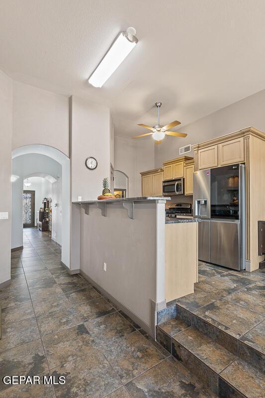 kitchen with ceiling fan, stainless steel appliances, a kitchen bar, and kitchen peninsula