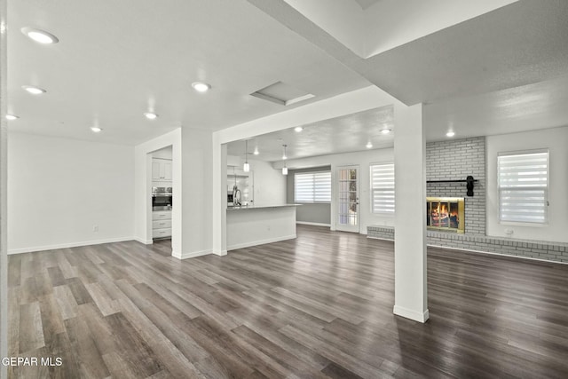 unfurnished living room with dark hardwood / wood-style floors, sink, and a fireplace