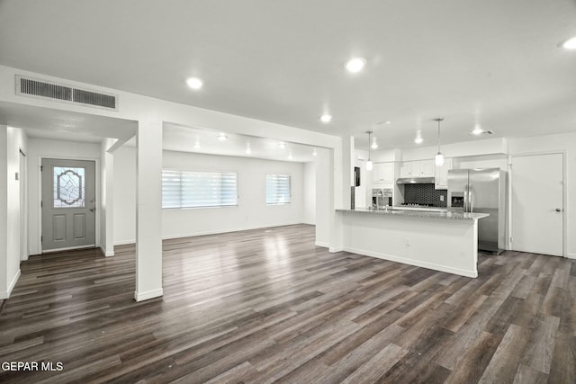 unfurnished living room with dark wood-type flooring and plenty of natural light