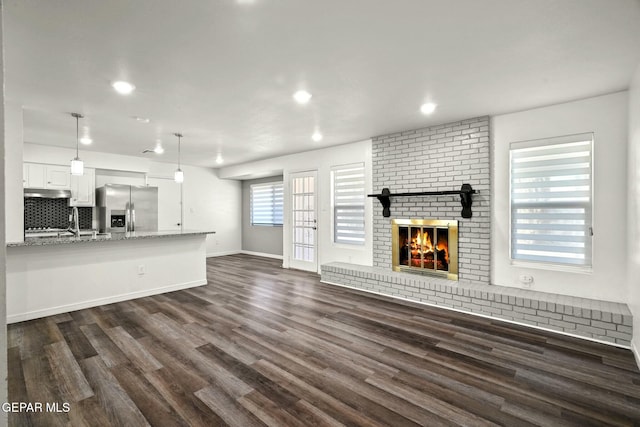 unfurnished living room with dark hardwood / wood-style flooring, sink, and a fireplace