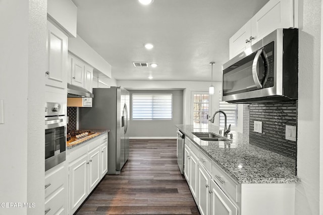 kitchen featuring sink, pendant lighting, stainless steel appliances, decorative backsplash, and white cabinets