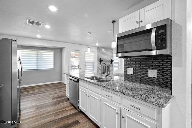 kitchen with white cabinetry, appliances with stainless steel finishes, sink, and decorative light fixtures