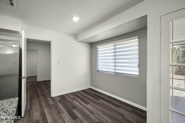 unfurnished bedroom with stainless steel refrigerator and dark hardwood / wood-style flooring